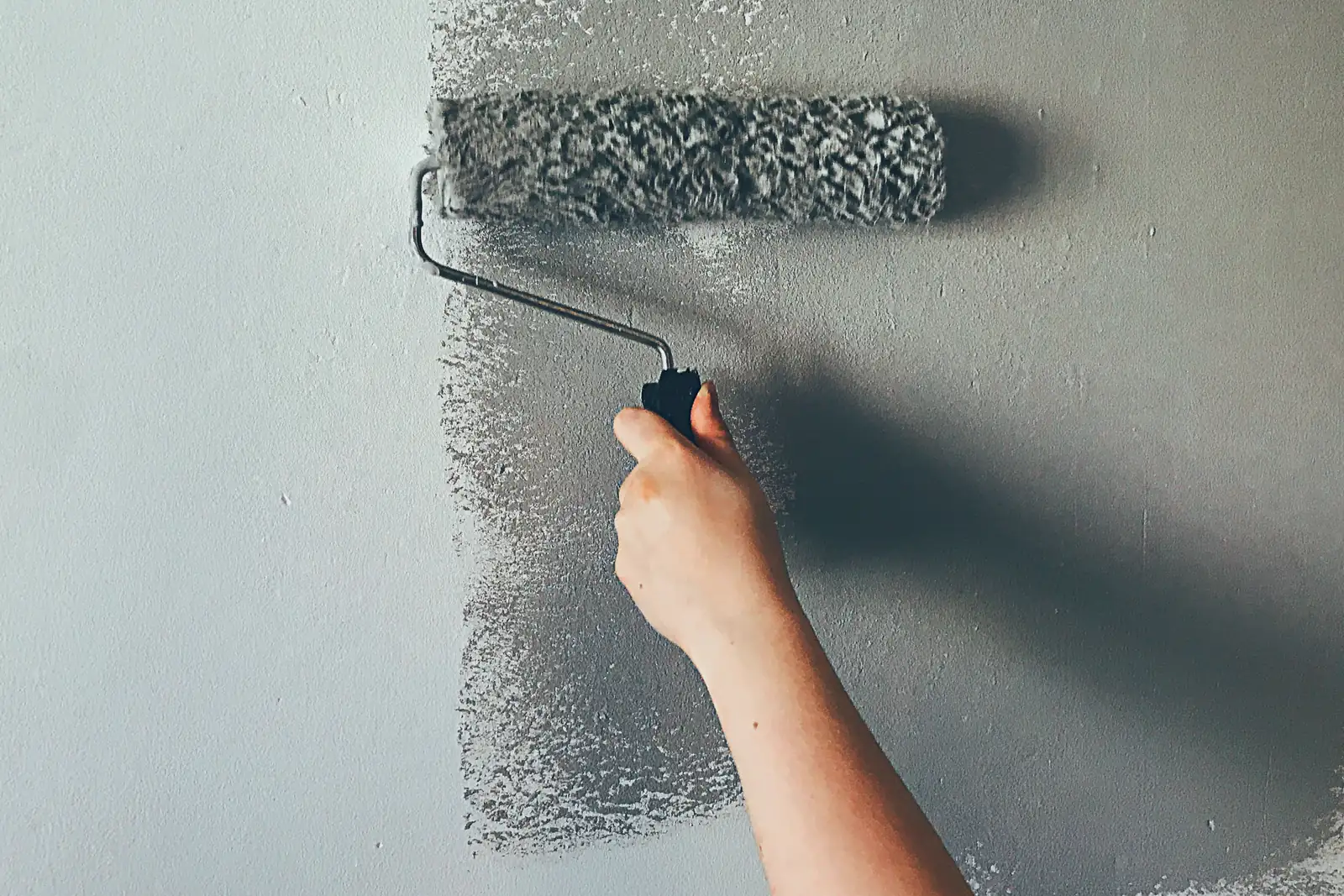 Rodillo con pintura gris sobre la pared de un piso en Burlada