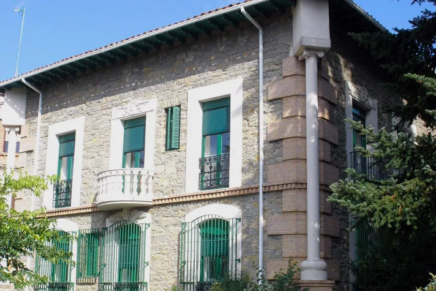 Casa de piedra con contraventanas verdes en Burlada